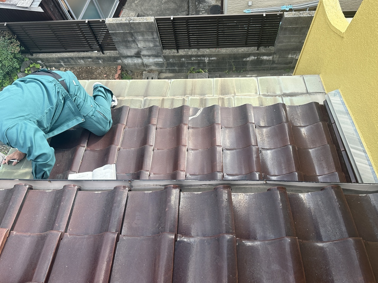 北九州市の戸建て住宅でドローン点検を実施する外装リフォーム検査士。屋根の頂上や死角を安全に精密調査。