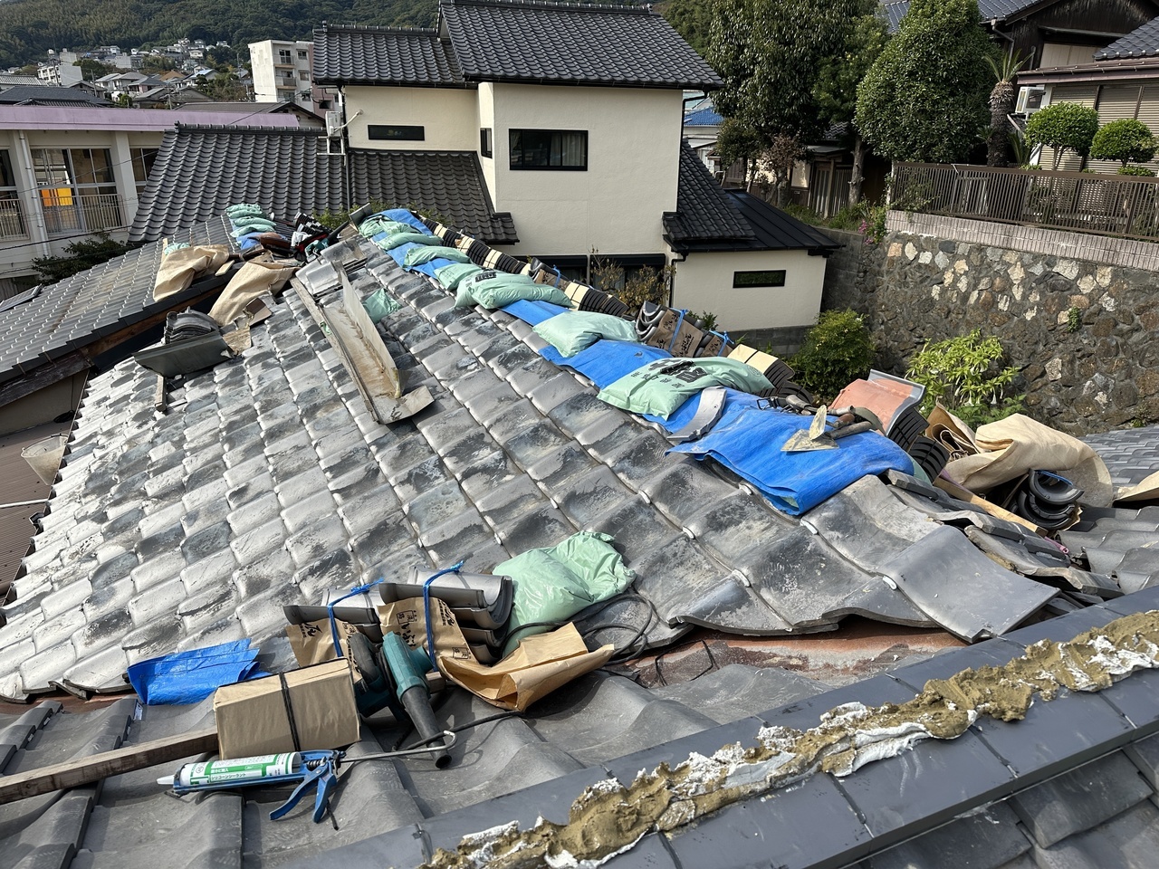 北九州の屋根修理：棟瓦の解体後にブルーシートと重りで雨漏り対策を行う養生作業