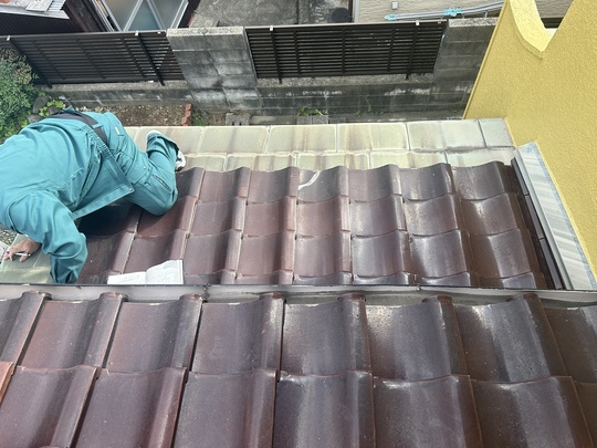 北九州市の戸建て住宅でドローン点検を実施する外装リフォーム検査士。屋根の頂上や死角を安全に精密調査。